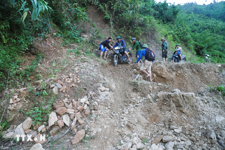 Lực lượng chức năng trong hành trình vượt qua các điểm sạt lở, sụt lún để đến bản Na Ngân bị cô lập. (Ảnh: Xuân Tiến/TTXVN)