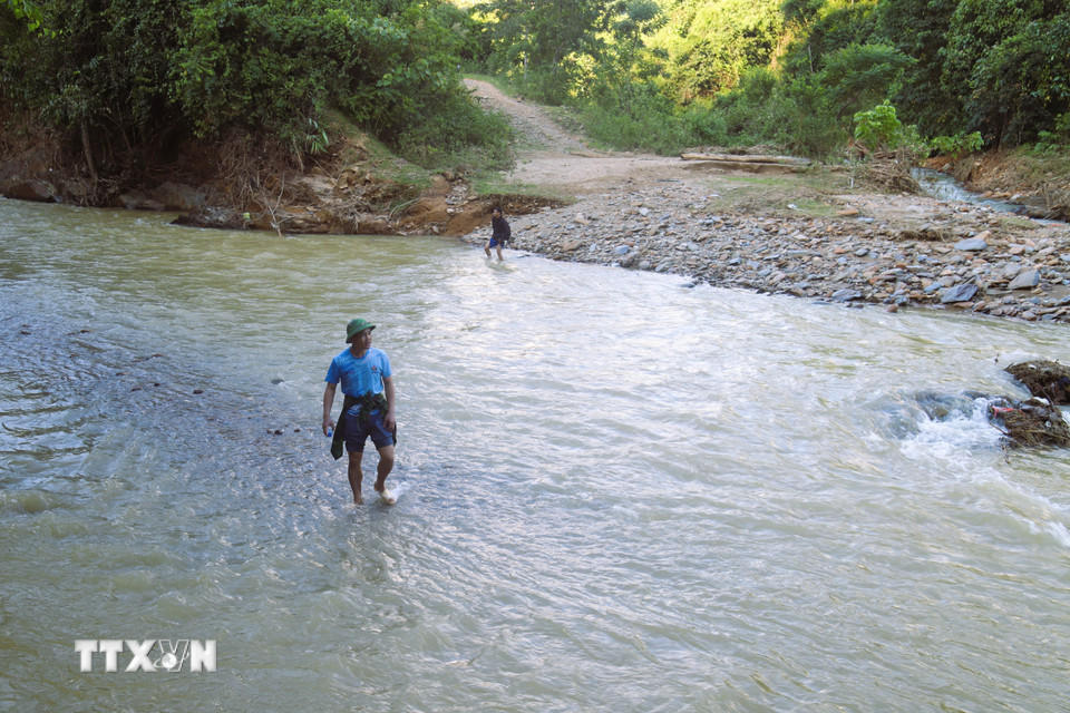 Cầu gỗ bắc qua suối Nậm Ngân, đoạn giao cắt với khe Hưng bị lũ cuốn trôi, đoàn công tác phải lội bộ qua suối để đến bản Na Ngân. (Ảnh: Xuân Tiến/TTXVN)