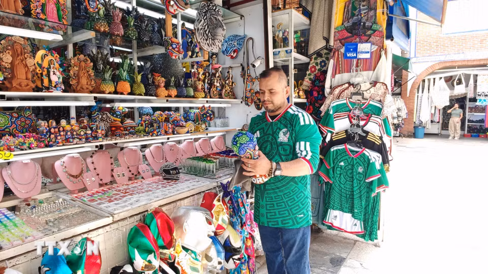 Chủ cửa hàng chỉnh trang mô hình cúp FIFA World Cup 2026 mang đậm sắc màu nghệ thuật thủ công Huichol truyền thống của Mexico. (Ảnh: Phương Lan/TTXVN)