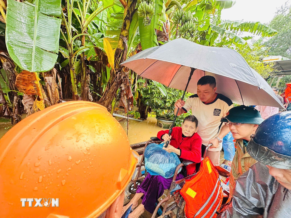 Lực lượng chức năng xã Tịnh Khê hỗ trợ di dời người dân đến nơi an toàn. (Ảnh: TTXVN phát)