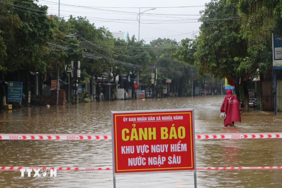 Nhiều tuyến đường tại xã Nghĩa Hành ngập sâu, chính quyền dựng rào chắn, căng dây cảnh báo cấm qua lại. (Ảnh: Đinh Hương/TTXVN)