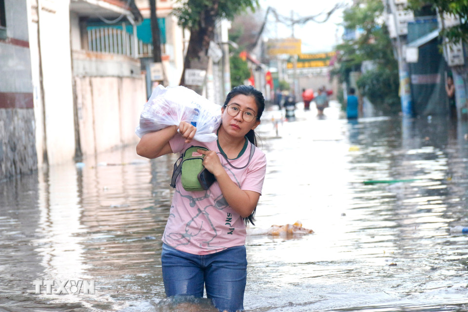 Người dân di chuyển đồ đạc tại khu vực ngập sâu đến nơi ở khác. (Ảnh: Nguyễn Thanh/TTXVN)