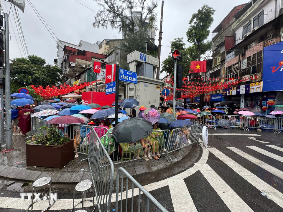 Bất chấp cơn mưa lớn, hàng nghìn người dân vẫn đổ về các tuyến phố chờ đợi chào đón các khối diễu binh sơ duyệt cho Đại lễ 80 năm Quốc khánh. (Ảnh: Minh Quyết/TTXVN)