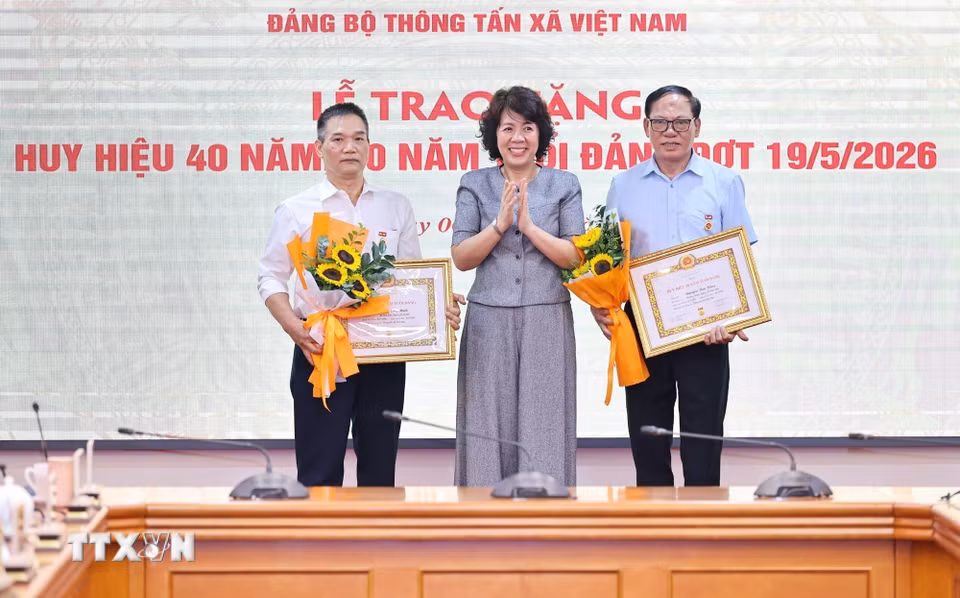 Đồng chí Nguyễn Thị Hoàng Vân, Phó Bí thư Đảng ủy, Trưởng Ban Tuyên giáo và Dân vận Đảng ủy các cơ quan Đảng Trung ương trao tặng Huy hiệu 30 năm, 40 năm tuổi Đảng cho đồng chí Phạm Huy Minh, Đảng bộ Ban Biên tập Ảnh và đồng chí Nguyễn Văn Bằng, Chi bộ Trung tâm Hợp tác quốc tế thông tấn. (Ảnh: Minh Đức/TTXVN)