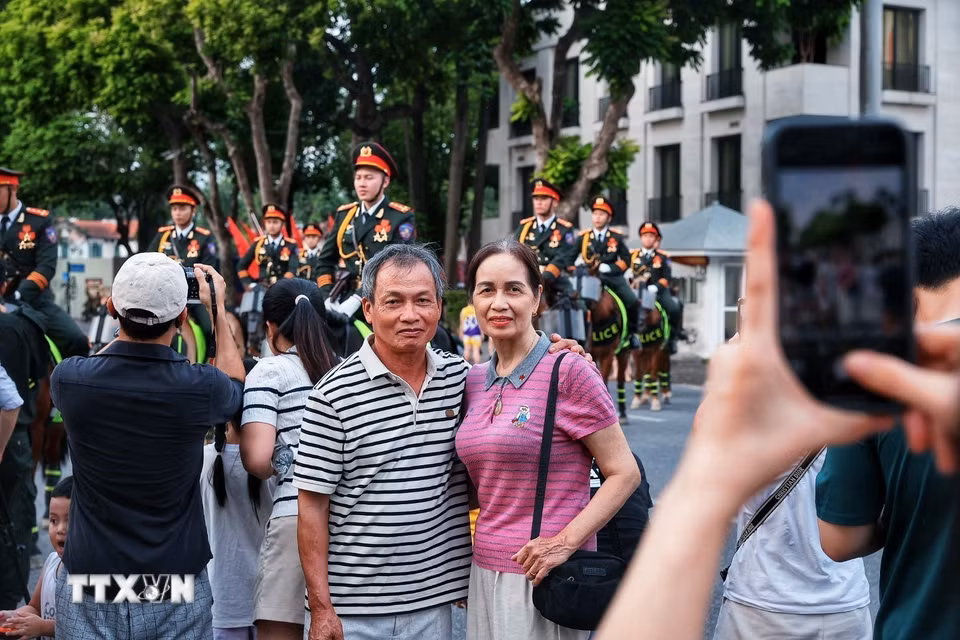 Người dân lưu lại những khoảnh khắc cùng lực lượng Cảnh sát cơ động Kỵ binh trong buổi tổng duyệt chương trình “81 mùa bình yên.” (Ảnh: Phạm Tuấn Anh/TTXVN)