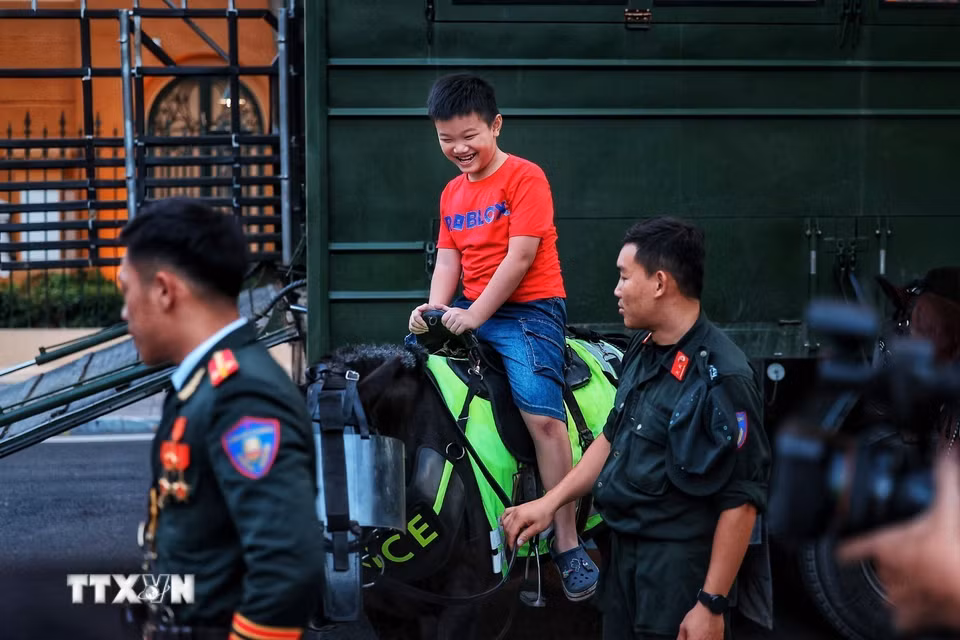 Niềm vui của một em nhỏ khi được trải nghiệm cưỡi ngựa dưới sự hướng dẫn, hỗ trợ của cán bộ, chiến sỹ Cảnh sát cơ động kỵ binh. (Ảnh: Phạm Tuấn Anh/TTXVN)