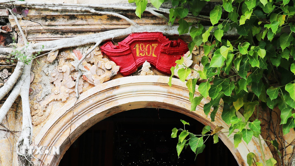 Vòm cửa giữa ngôi đình được đắp hình cuốn thư nhỏ, ghi năm 1907, năm ngôi đình được hoàn thành. (Ảnh: Hữu Chí/TTXVN)