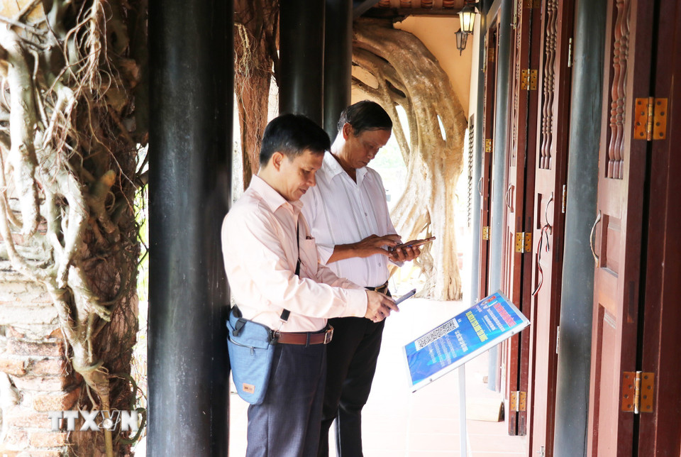 Du khách quét mã QR để tìm hiểu về Đình Tân Đông (Đồng Tháp). (Ảnh: Hữu Chí/TTXVN)