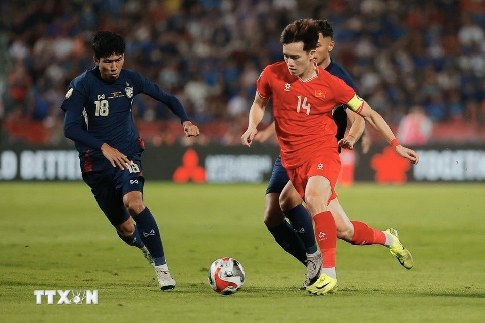 Đội trưởng Hoàng Đức (14) đi bóng qua sự truy cản của cầu thủ Thái Lan. (Ảnh: Minh Quyết/TTXVN)