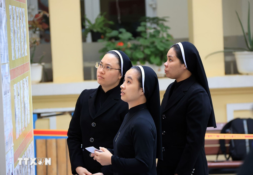 Các nữ tu dòng Mến Thánh Giá 31 Nhà Chung xem danh sách những người ứng cử đại biểu tại khu vực bỏ phiếu số 1, phường Hoàn Kiếm. (Ảnh: Tuấn Anh/TTXVN)