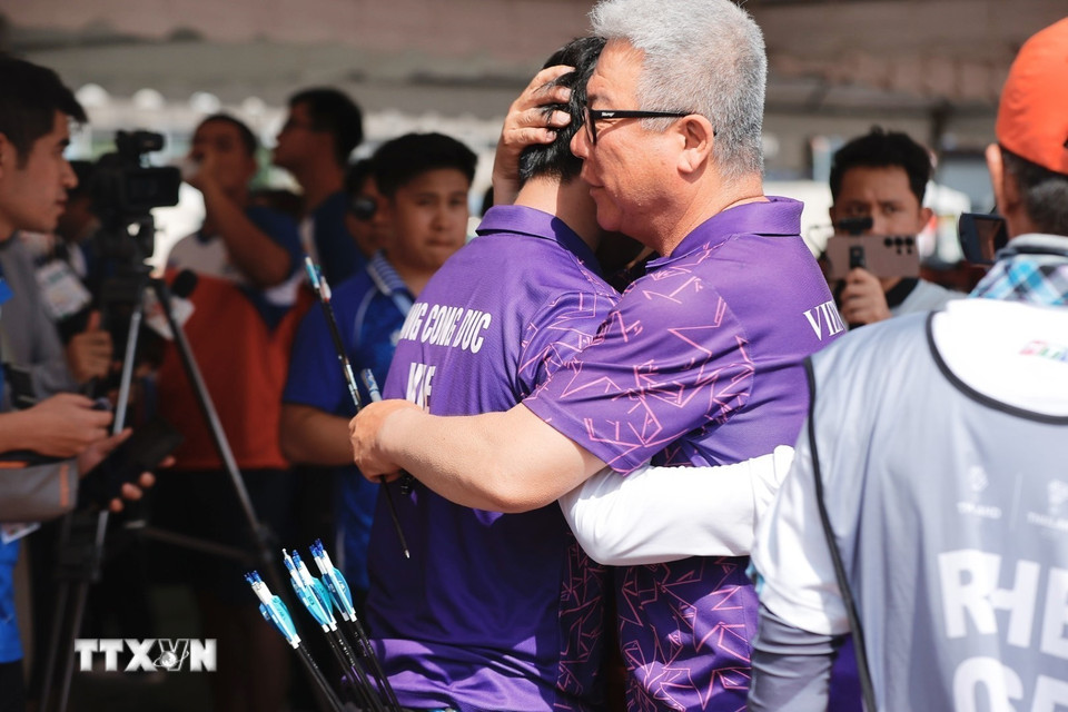 Huấn luyện viên động viên Đặng Công Đức sau khi hoàn thành thi nội dung cung 3 dây đôi nam nữ hỗn hợp. (Ảnh: Minh Quyết/TTXVN)