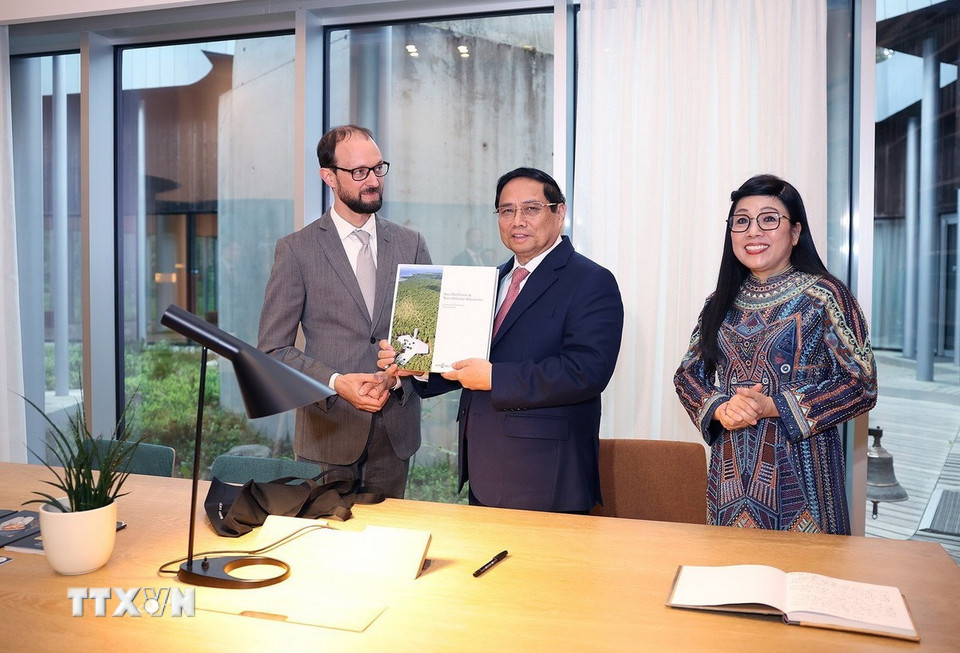 Đại diện gia đình nhà soạn nhạc Arvo Pärt tặng Thủ tướng Phạm Minh Chính cuốn sách về Nhà soạn nhạc cổ điển người Estonia Arvo Pärt. (Ảnh: Dương Giang/TTXVN)