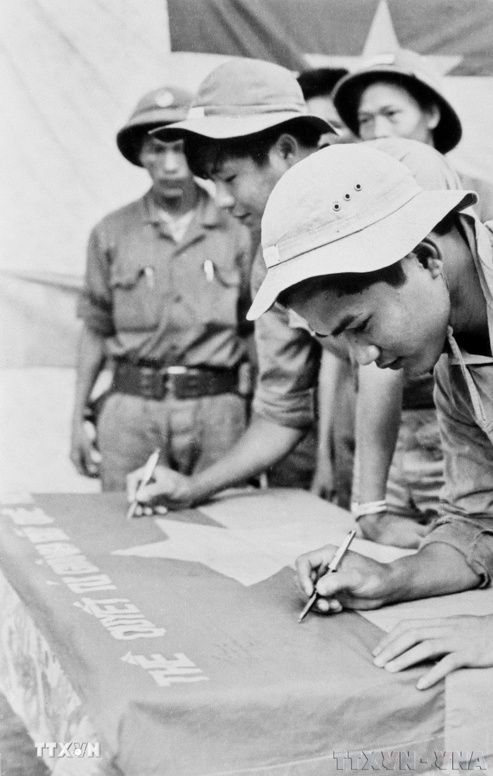 Các chiến sỹ tổ mở cửa quân giải phóng Quảng Ngãi ký tên lên lá cờ thề quyết tử giành giữ quê hương, trước khi mở màn vào chiến dịch Xuân 1975. (Ảnh: Thanh Tụng/TTXVN)