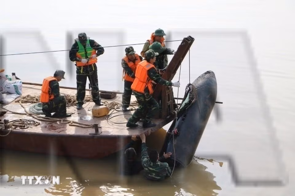 Lực lượng chức năng tiến hành trục vớt quả bom chưa nổ dưới sông Hồng, cách chân cầu Long Biên về phía thượng lưu khoảng 600m. Quả bom dài 1,6m, có đường kính khoảng 35cm, nằm sâu 2m. (Ảnh: Thành Đạt/TTXVN)