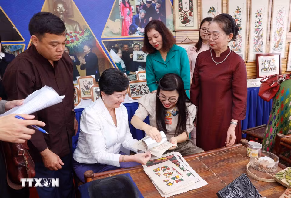 Bà Lê Thị Bích Trân, Phu nhân Thủ tướng Chính phủ Phạm Minh Chính và nhóm Phụ nữ cộng đồng ASEAN tại Hà Nội trải nghiệm làm tranh dân gian Đông Hồ. (Ảnh: Phạm Kiên/TTXVN)