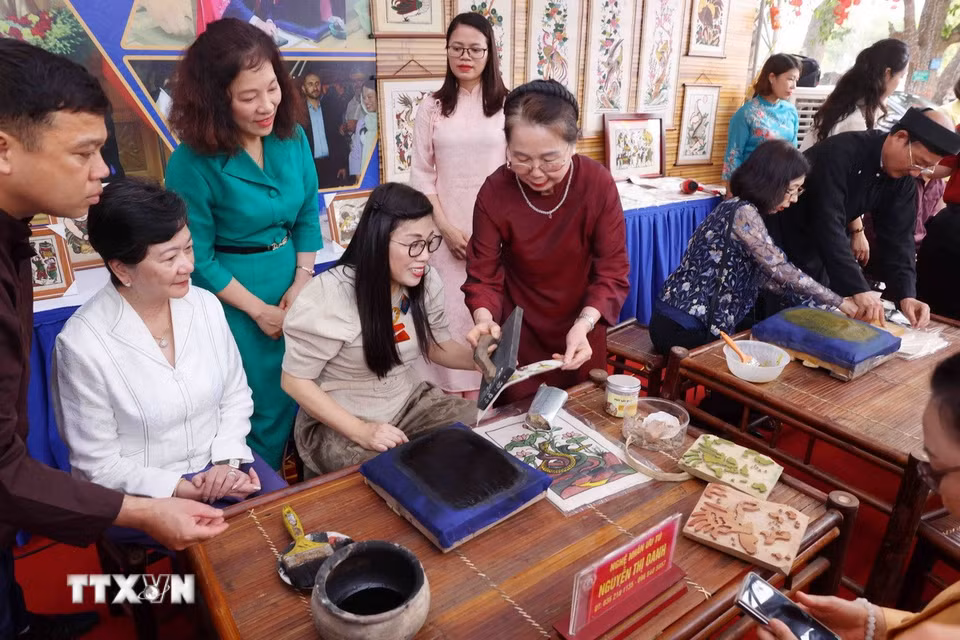Bà Lê Thị Bích Trân, Phu nhân Thủ tướng Chính phủ Phạm Minh Chính và nhóm Phụ nữ cộng đồng ASEAN tại Hà Nội trải nghiệm làm tranh dân gian Đông Hồ. (Ảnh: Phạm Kiên/TTXVN)