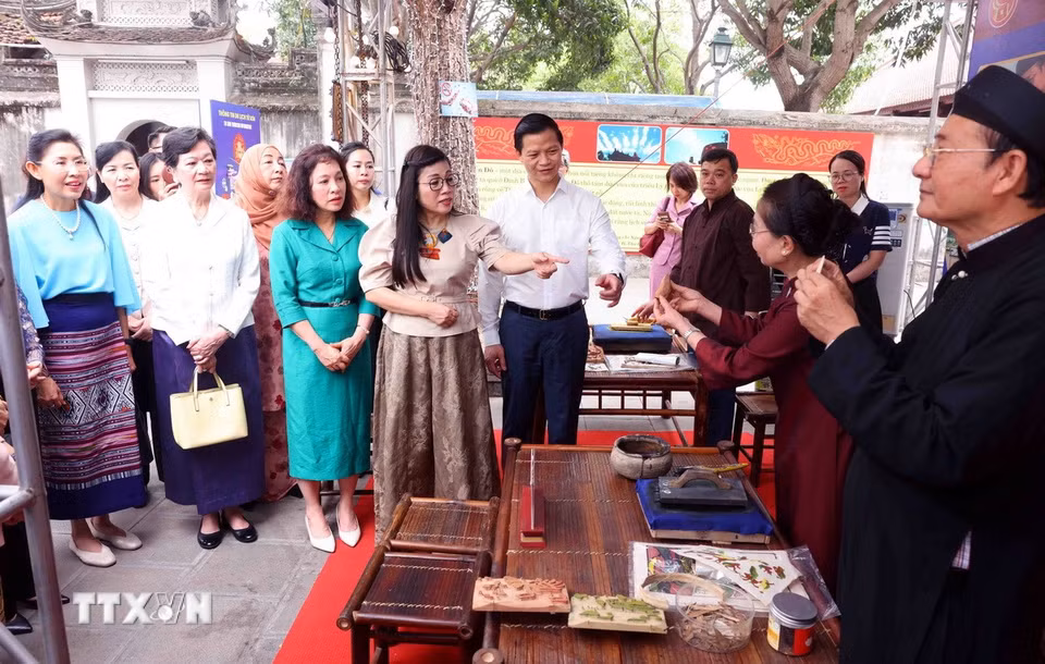 Bà Lê Thị Bích Trân, Phu nhân Thủ tướng Chính phủ Phạm Minh Chính và nhóm Phụ nữ cộng đồng ASEAN tại Hà Nội nghe các nghệ nhân giới thiệu về làm tranh dân gian Đông Hồ. (Ảnh: Phạm Kiên/TTXVN)