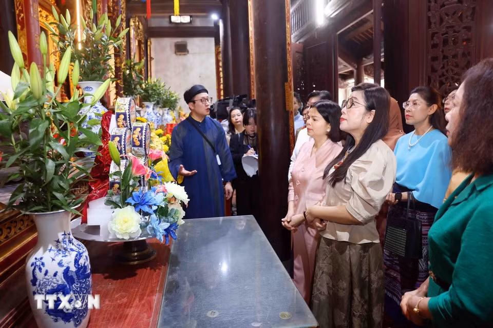 Bà Lê Thị Bích Trân, Phu nhân Thủ tướng Chính phủ Phạm Minh Chính và Nhóm Phụ nữ cộng đồng ASEAN tại Hà Nội nghe giới thiệu về lịch sử Đền Đô. (Ảnh: Phạm Kiên/TTXVN)