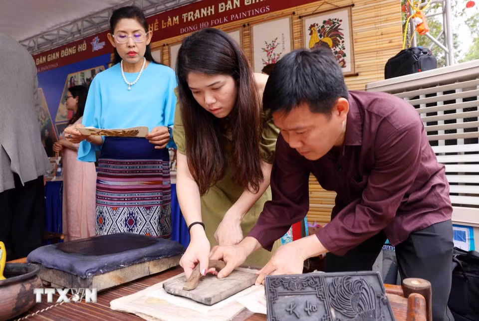 Các đại biểu thuộc nhóm Phụ nữ cộng đồng ASEAN tại Hà Nội trải nghiệm làm tranh dân gian Đông Hồ. (Ảnh: Phạm Kiên/TTXVN)
