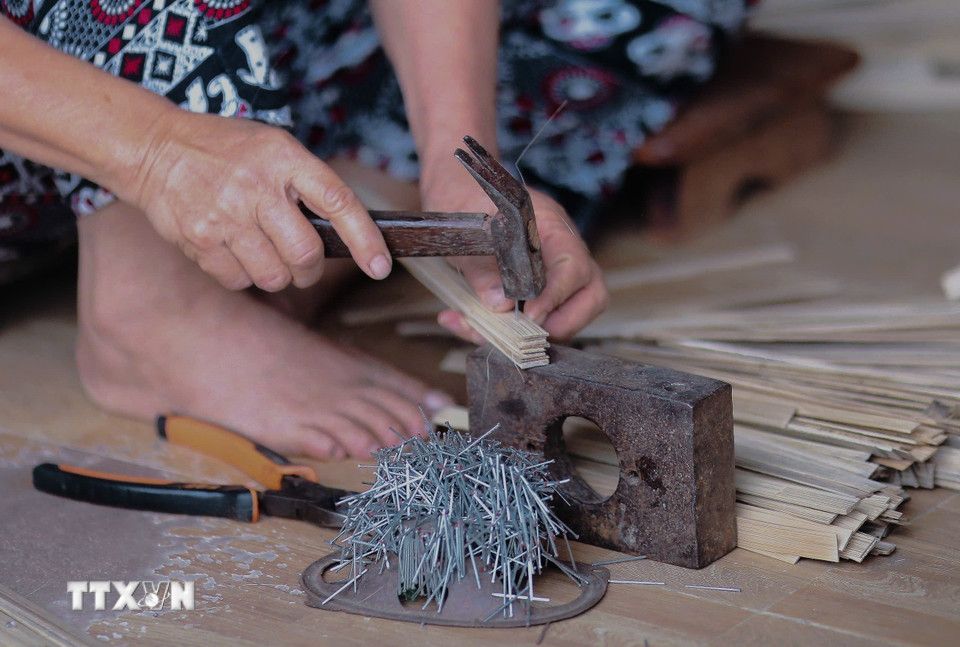 Đóng đinh cố định nan quạt bằng phương pháp thủ công, đảm bảo độ chắc chắn cho sản phẩm. (Ảnh: Phương Anh/TTXVN phát)