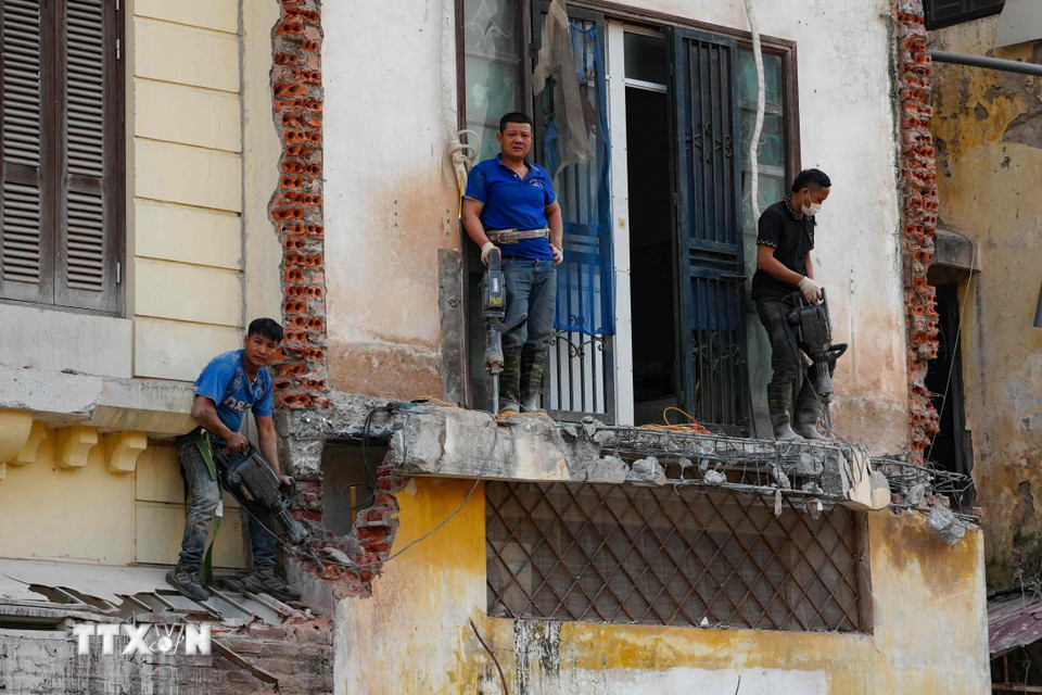 Một nhóm thợ xây dựng sử dụng máy khoan để mở mặt tiền mới cho một ngôi nhà cũ. (Ảnh: Vũ Quang/TTXVN)