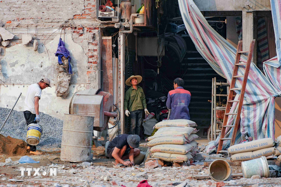 Các thợ xây và máy trộn bê tông hoạt động hết công suất. (Ảnh: Vũ Quang/TTXVN)