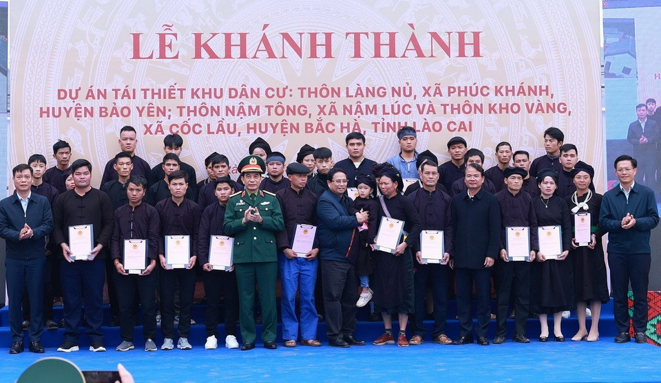 Thủ tướng Phạm Minh Chính và lãnh đạo địa phương trao chứng nhận quyền sử dụng đất tại nơi ở mới cho các gia đình thôn Làng Nủ. (Ảnh: Dương Giang/TTXVN)