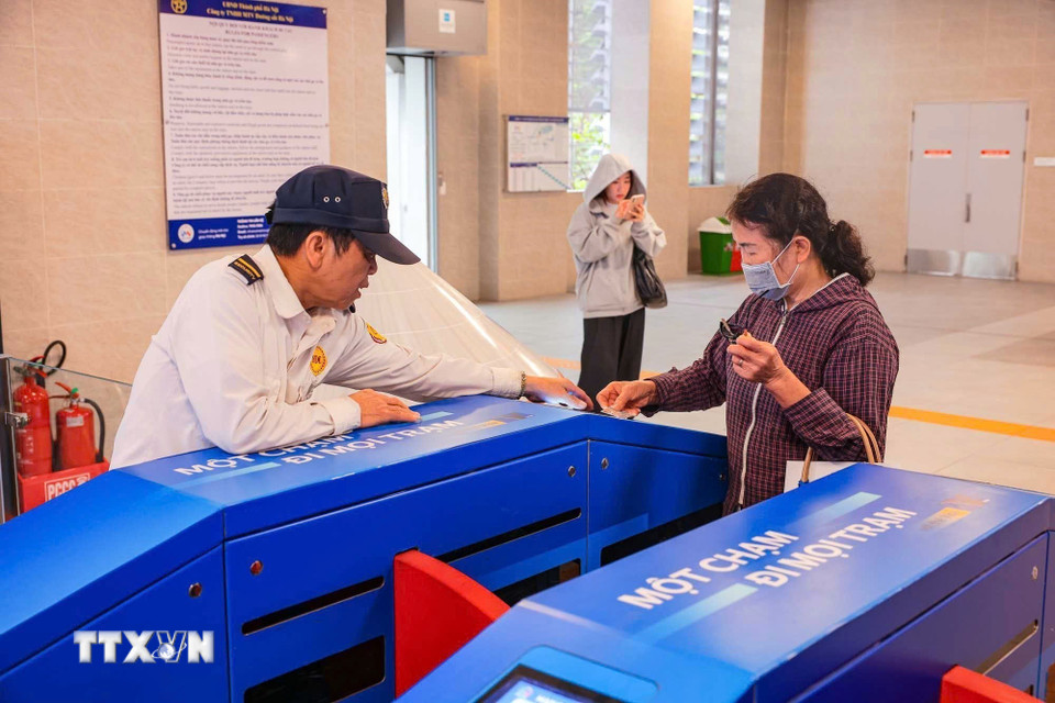 Nhân viên hướng dẫn khách hàng lớn tuổi sử dụng thẻ khi đi đường sắt trên cao. (Ảnh: Hoàng Hiếu/TTXVN)