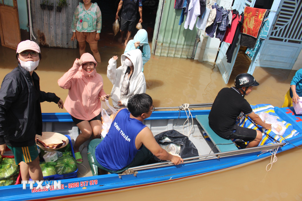 Các nhóm thiện nguyện dùng xuồng chèo đến phát cơm tận tay người dân vùng ngập nghiêm trọng. (Ảnh: Hồng Hiếu/TTXVN)