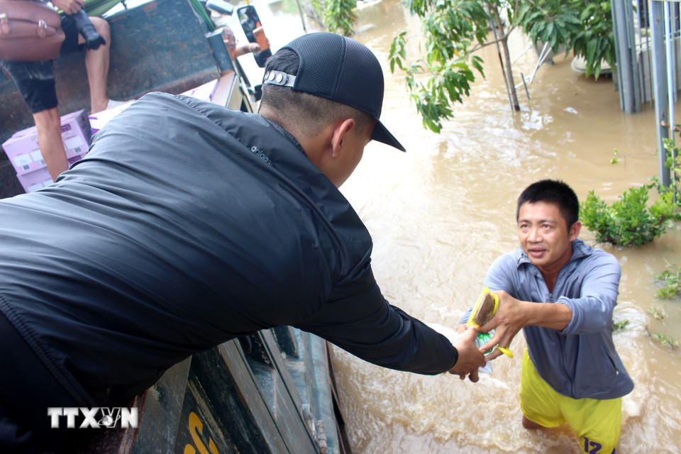 Nhóm thiện nguyện dùng xe ben phát cơm cho người dân vùng ngập Hàm Thắng. (Ảnh: Hồng Hiếu/TTXVN)