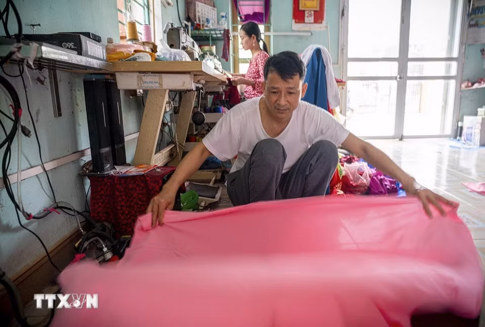 Một trong những đặc trưng khác làm nên thương hiệu của làng Trạch Xá đó chính là việc không dùng chỉ công nghiệp mà dùng chính những sợi tơ gỡ ra từ tấm vải may áo dài. Với cách làm này, chiếc áo sẽ đồng nhất về chất liệu, không bị cứng hay co giãn khi giặt, tà áo luôn giữ được sự thướt tha, mềm mại. (Ảnh: Khánh Hòa/TTXVN)