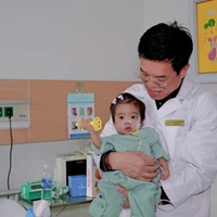 Phó giáo sư Lê Văn Thành thăm bé Di sau hơn một tháng phẫu thuật. (Ảnh: PV/Vietnam+)