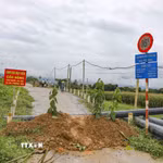 Lực lượng chức năng cắm biển cảnh báo, ngăn người và phương tiện qua cầu C9 sau khi phát hiện mố cầu bị xói lở nghiêm trọng. (Ảnh: Xuân Tư/TTXVN)
