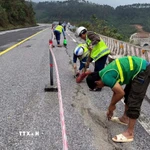 Lực lượng công nhân tiến hành nhồi sợi dây đay vào khe nứt rồi đổ nhựa đường nhằm ngăn nước thấm xuống phía dưới tại sự cố nứt đường trên Quốc lộ 1A, đoạn qua Đèo Ngang. (Ảnh: TTXVN phát)