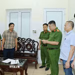Cơ quan Cảnh sát điều tra, Công an tỉnh khám xét nơi làm việc của Hoàng Văn Huấn (áo kẻ). (Ảnh: TTXVN phát)