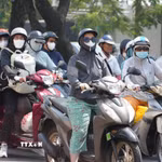 Người dân mặc đồ bảo hộ chống nắng, khi di chuyển trên đường. (Ảnh: Nguyên Lý/TTXVN)