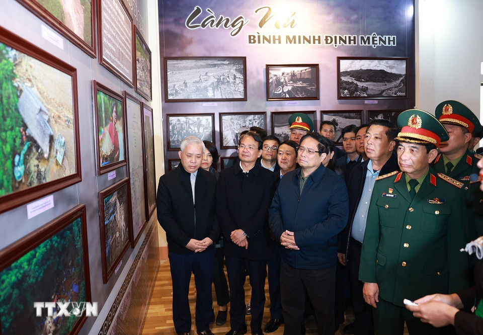 Thủ tướng Phạm Minh Chính tham quan trưng bày ảnh, hiện vật về trận lũ quét tại Nhà văn hóa thôn Làng Nủ. (Ảnh: Dương Giang/TTXVN)