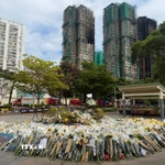 Hàng nghìn bông hoa được người dân mang đến gần hiện trường vụ cháy để bày tỏ niềm thương tiếc với các nạn nhân. (Ảnh: Mạc Luyện/TTXVN)