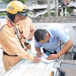 Cảnh sát giao thông lập biên bản một trường hợp tài xế xe khách vi phạm. (Ảnh: Linh Sơn/TTXVN)