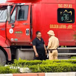 Cán bộ Đội Cảnh sát giao thông đường bộ số 15 (Phòng Cảnh sát giao thông Hà Nội) tuyên truyền, hướng dẫn lái xe chấp hành quy định về tải trọng và lộ trình lưu thông đối với phương tiện ra, vào khu công nghiệp Nguyên Khê. (Ảnh: Trung Nguyên/TTXVN)