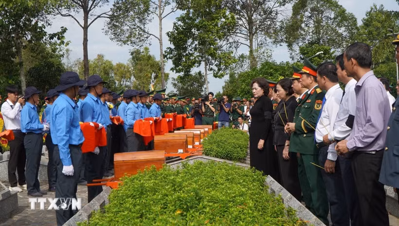 Các đại biểu thực hiện nghi thức đưa hài cốt liệt sỹ đến nơi an nghỉ. (Ảnh: Nhựt An/TTXVN) 