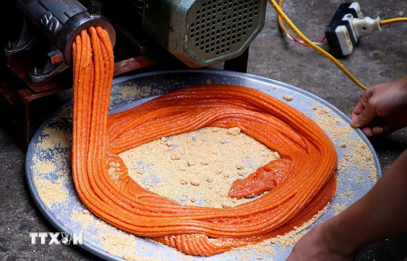 Xôi gấc làm bánh giầy được xay nhuyễn, có màu cam đỏ. (Ảnh: Thanh Hải/TTXVN)