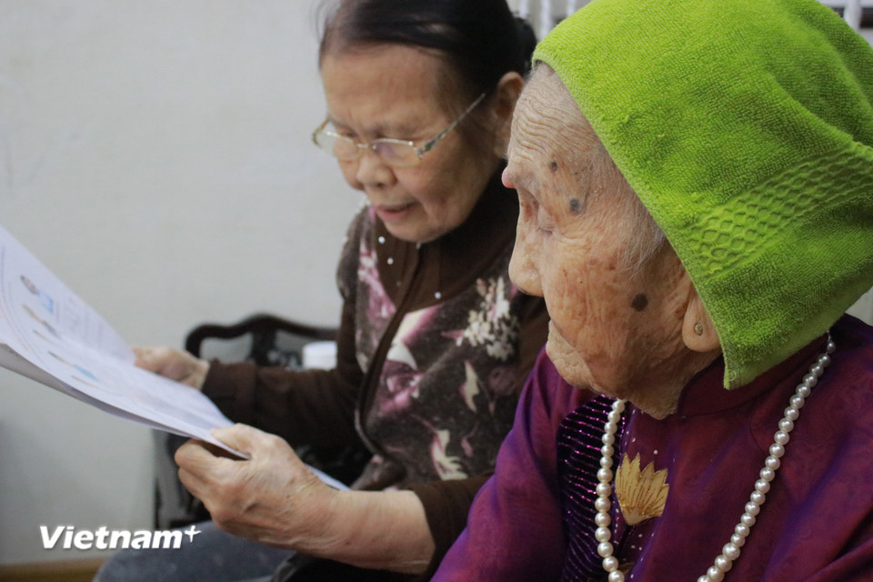 Trong những ngày trước bầu cử, bà Chiên thường đọc các thông tin cử tri cho Mẹ nghe. "Tiêu chí bỏ phiếu của gia đình là chọn ra người xứng đáng nhất, có tâm, có trí và có tầm," bà Chiên chia sẻ. Vào ngày 15/3, tổ bầu cử sẽ đưa hòm phiếu phụ tới cho công dân 99 tuổi này tự tay bỏ phiếu. (Ảnh: Minh Anh/Vietnam+)