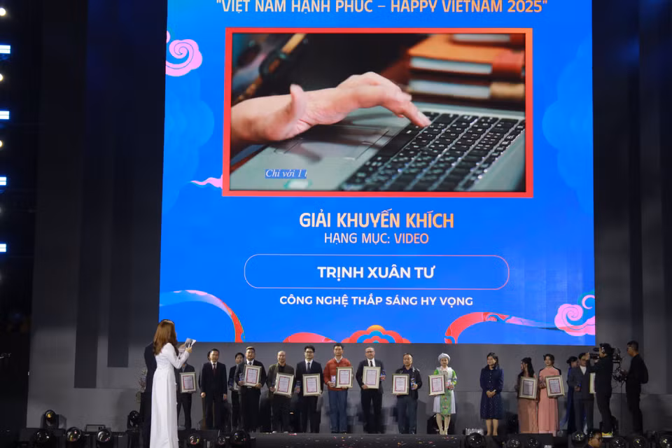 Tập thể tác giả, đại diện tác giả nhận giải Khuyến khích, trên màn hình là một hình ảnh trong tác phẩm video của phóng viên Trịnh Xuân Tư thuộc Thông tấn xã Việt Nam. (Ảnh: Minh Anh/Vietnam+)