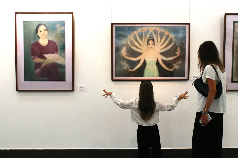 Hai mẹ con người Nga ngắm tranh "Đất nước nở hoa" của Lê Lam tại triển lãm. (Ảnh: Minh Anh/Vietnam+)