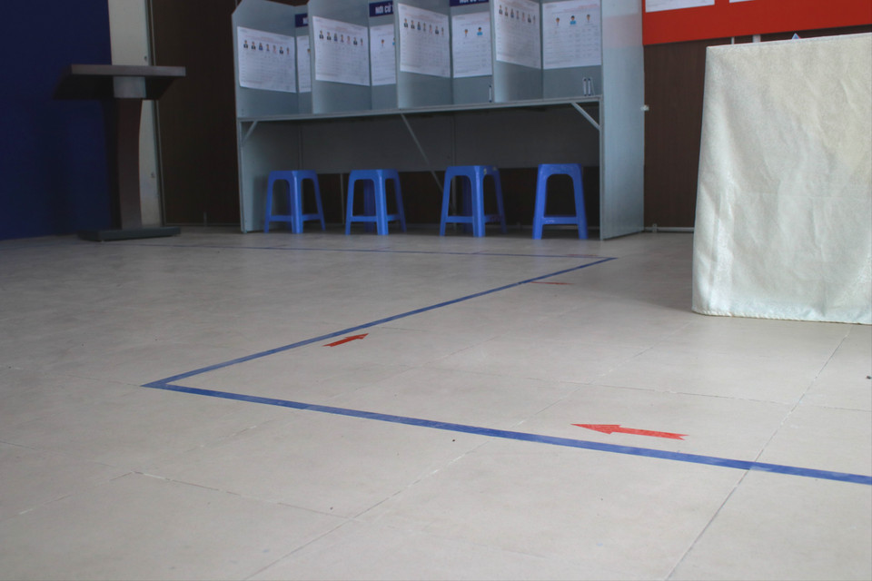 Để việc di chuyển được thuận lợi và hiệu quả, tổ bầu cử đã dán băng dính chỉ dẫn hướng đi, từ bàn phát phiếu bầu cử, đến khu vực viết phiếu, bỏ phiếu và cuối cùng là rời khỏi khu vực bầu cử. (Ảnh: Minh Anh/Vietnam+)