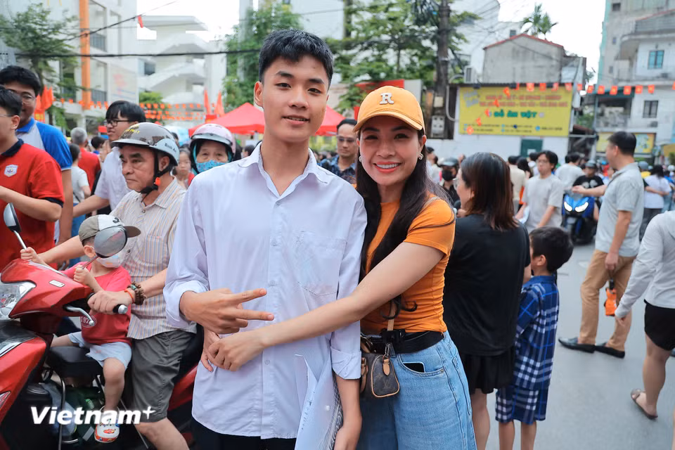 Một phụ huynh mừng rỡ ôm sỹ tử sau khi thấy con chia sẻ tương đối tích cực về bài thi vừa qua. (Ảnh: Hoài Nam/Vietnam+)
