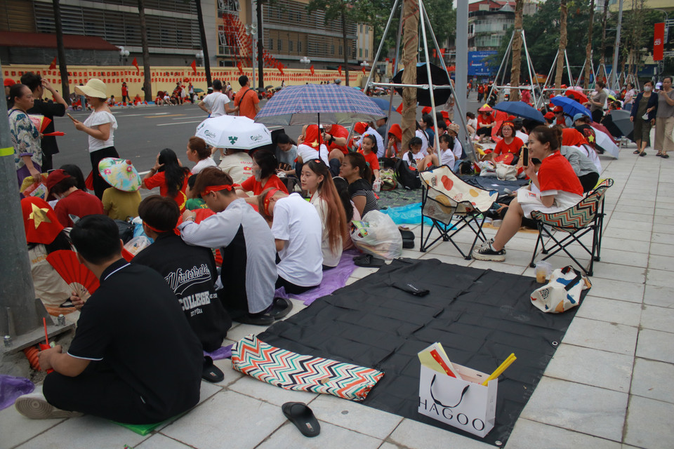 Người dân chuẩn bị sẵn thảm trải, ghế, áo mưa, đồ ăn nước uống để "cắm trại" giữ chỗ đẹp. (Ảnh: Minh Anh/Vietnam+)