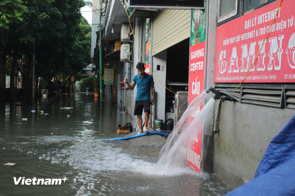 Hết bão, người dân sống khu vực chợ tạm Phú Đô cấp tập dọn dẹp, bơm nước từ trong ra ngoài nhà. (Ảnh: Minh Anh/Vietnam+)