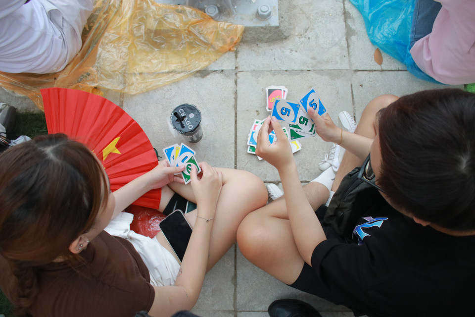 Hai bạn trẻ chơi Uno chờ đến "giờ G." (Ảnh: Minh Anh/Vietnam+)